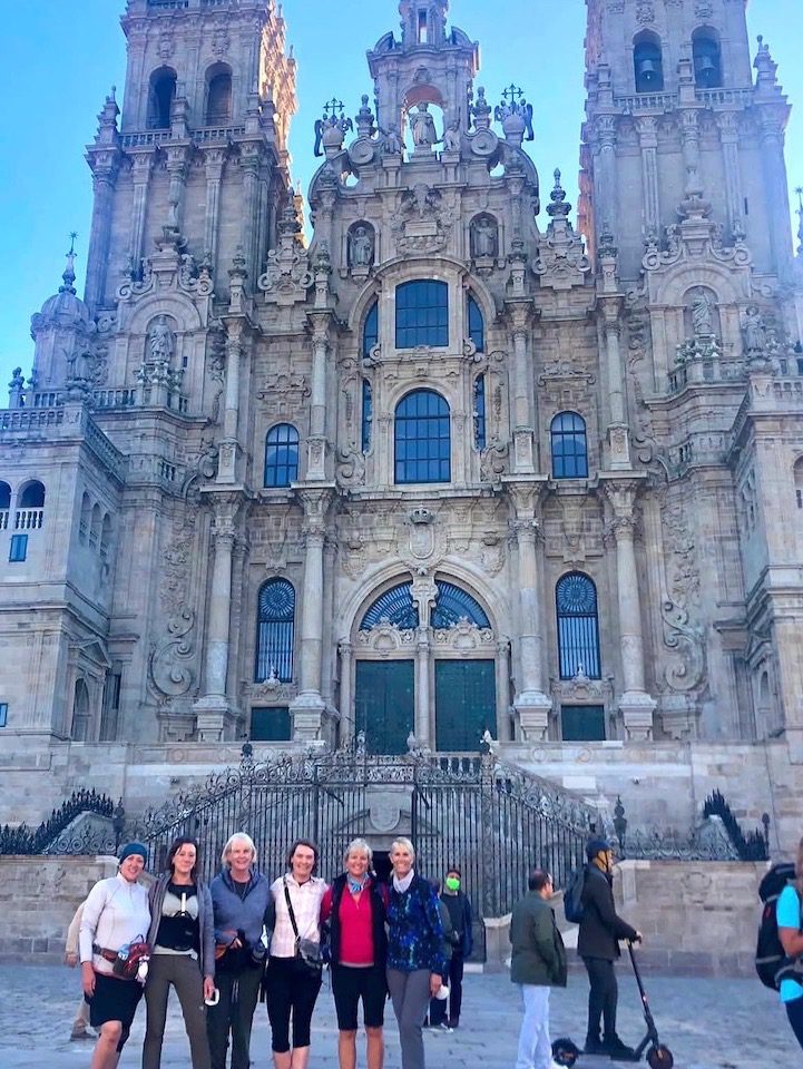 A group of women stand in front of the Santiago Cathedral after completing their trek along the Camino de Santiago
