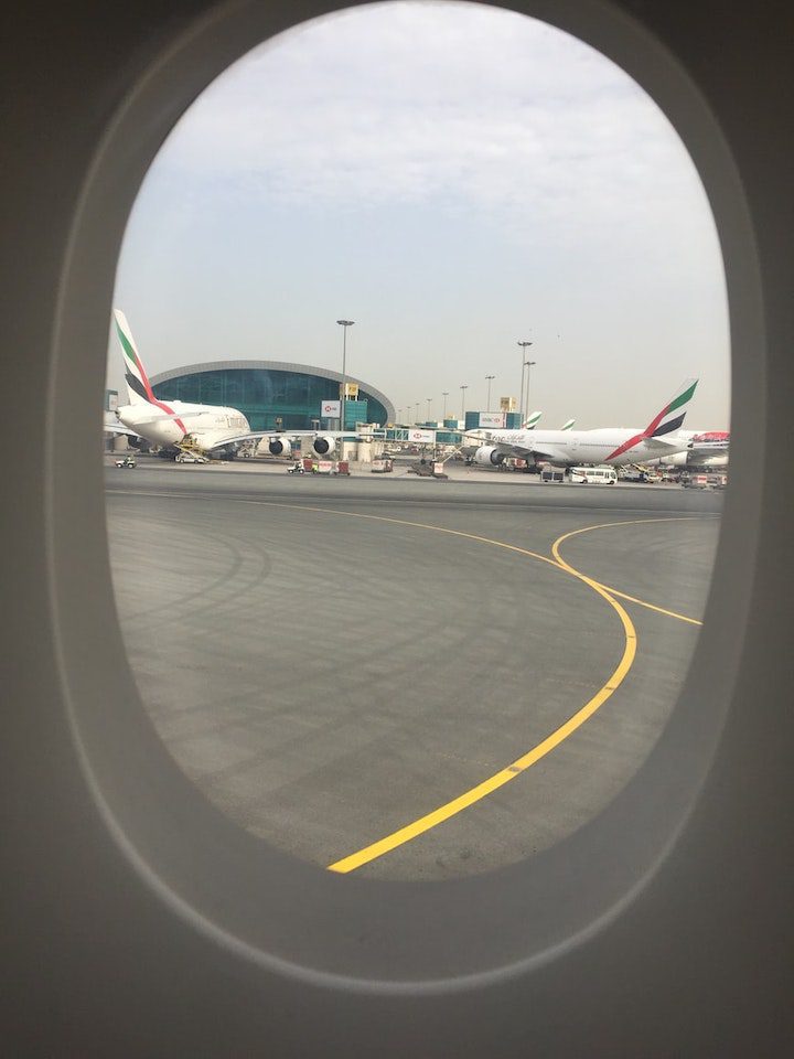 Looking through a plane window to two Emirates jets on the tarmac