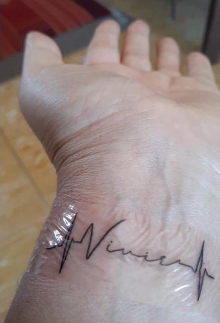 Christine Pope's latest tattoo, the word "vivre" on her wrist within the design of a heartbeat.