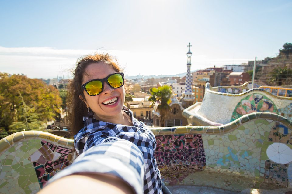 Barcelona, Spain. Beautiful girl looking at camera taking photo with smart phone smiling.