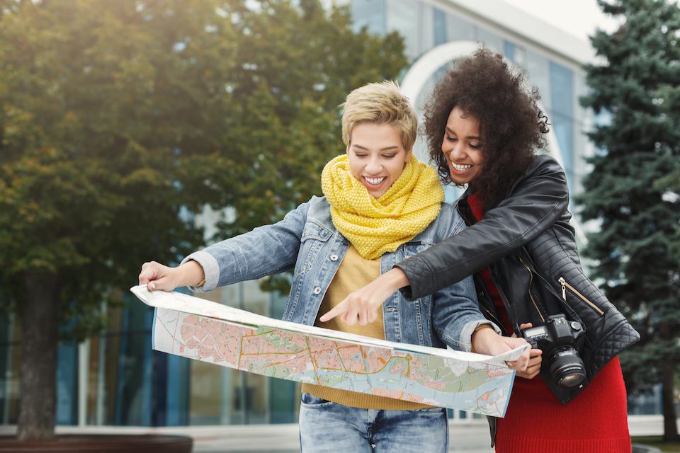 Two women friends outdoors with paper city map