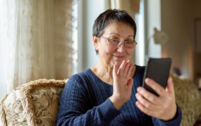 Senior woman in eyeglasses making video call on smartphone at home