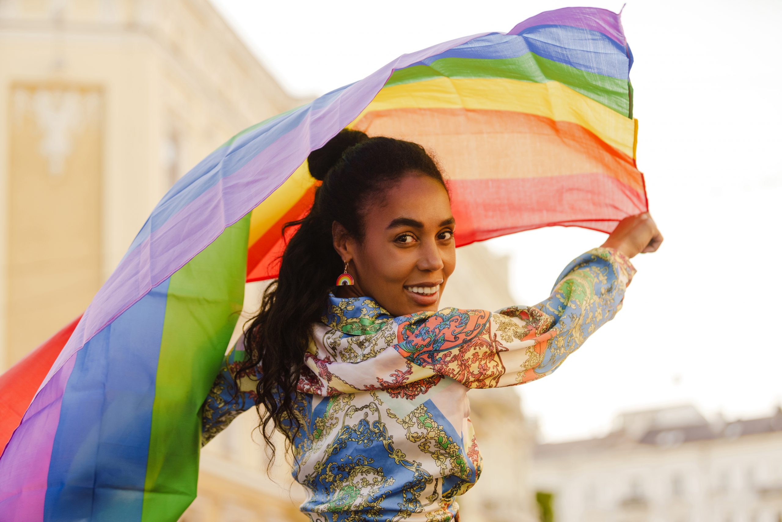 smiling black woman holding a rainbow flag