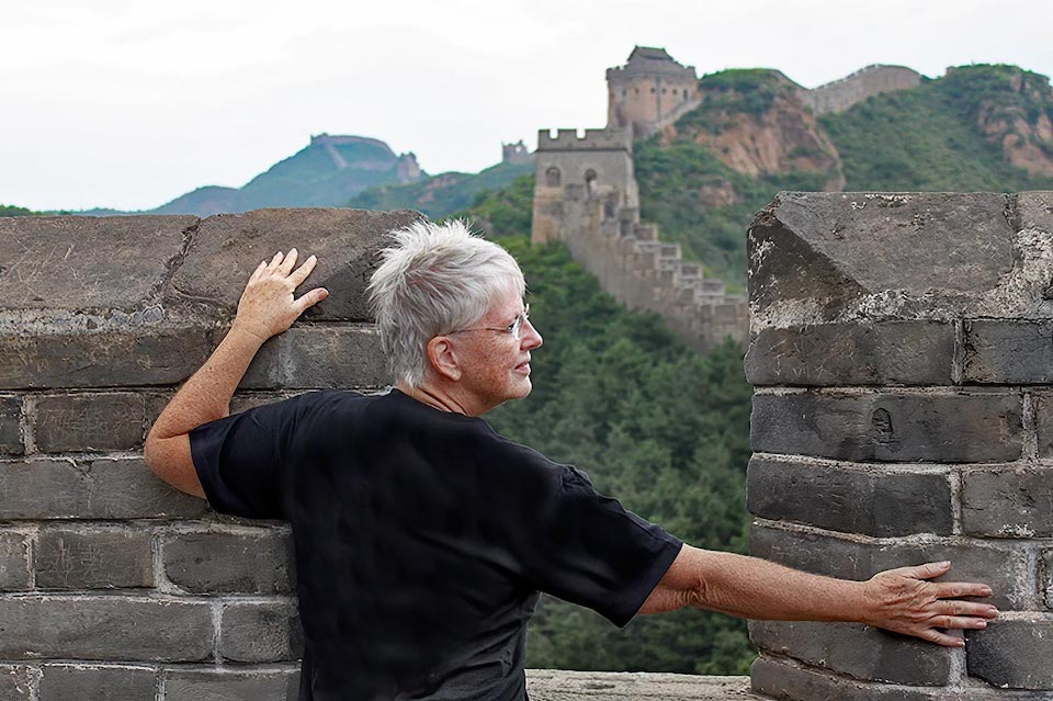 Barbara Weibel has her arms on the Great Wall of Chine