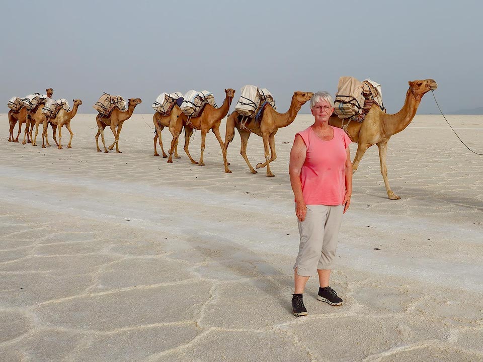 Barbara Weibel stands in front of a camel caravan at the Danakil Depression, Ethiopia