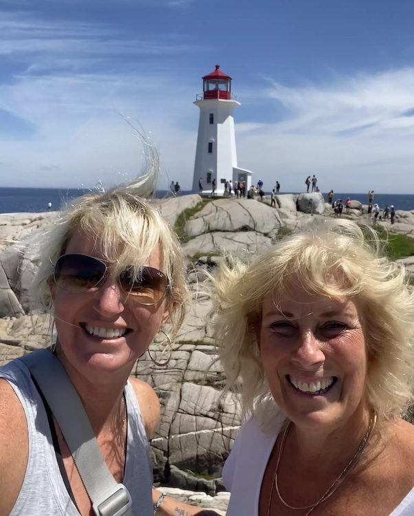 two women smiling in front of a lighthouse in Nova Scotia