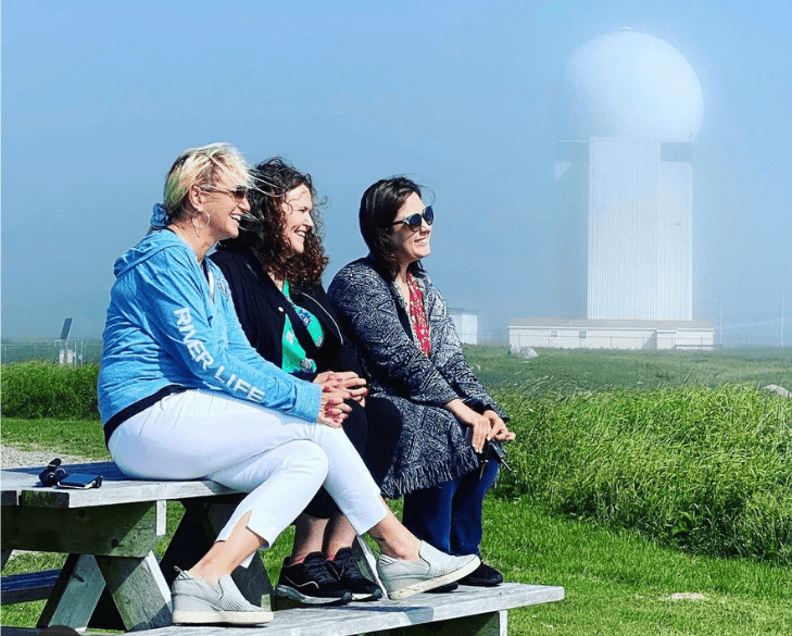 three woman laughing on a picnic table