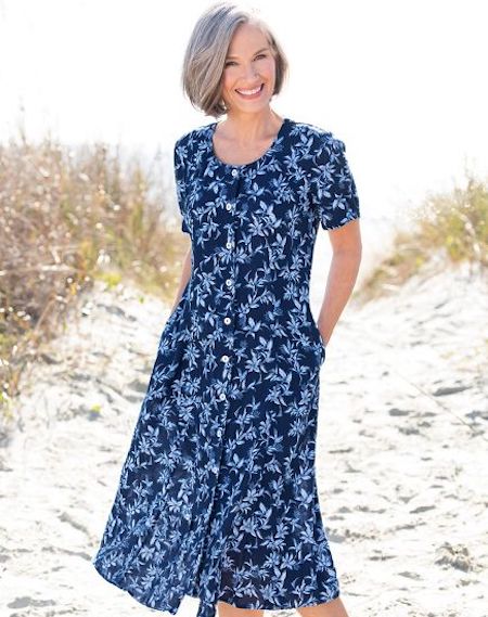 A woman wearing a travel-friendly floral dress on a beach