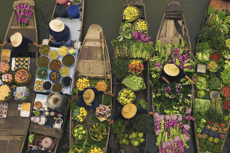Aerial view of a floating market on a canal in Bangkok, local boats laden with fresh food, moored close together.