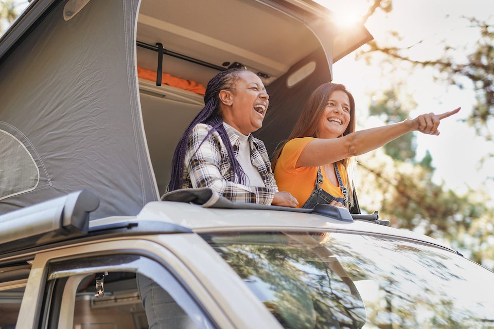 Friends enjoy vacation in the nautre with mini van - Mature women on a road trip with camper