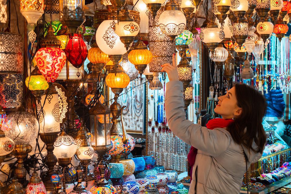Woman touching Turkish lamps for sale in the Grand Bazaar, Istanbul, Turkey