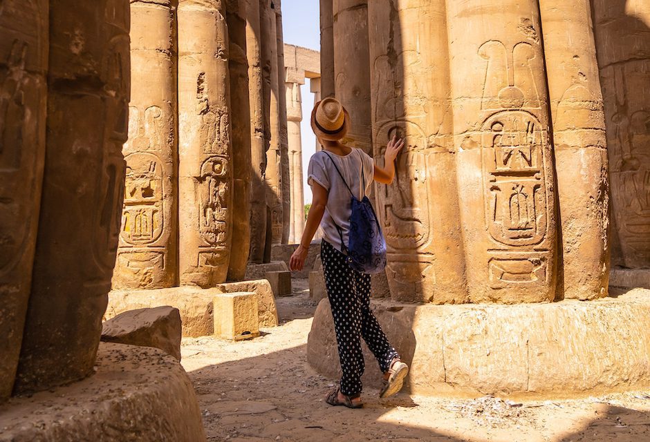 A tourist looking at ancient egyptian drawings on the columns of the Temple of Luxor, Egypt