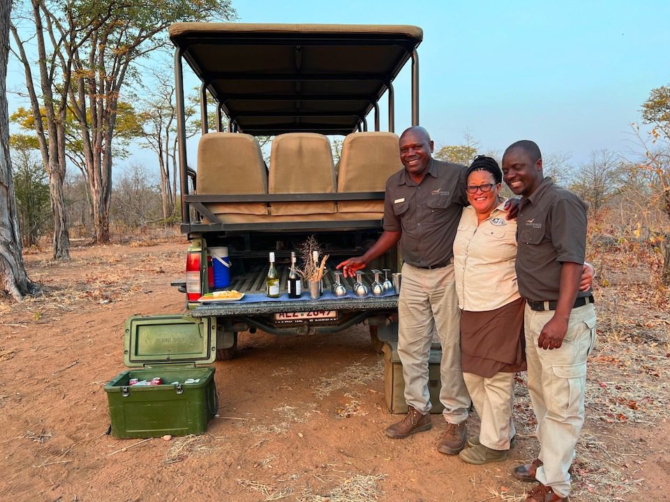 Three local guides stand next to the jeep on an African safari