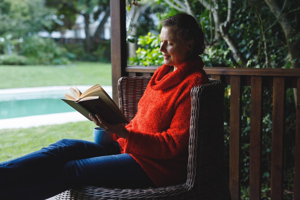 Woman in read sweater sitting reading a book