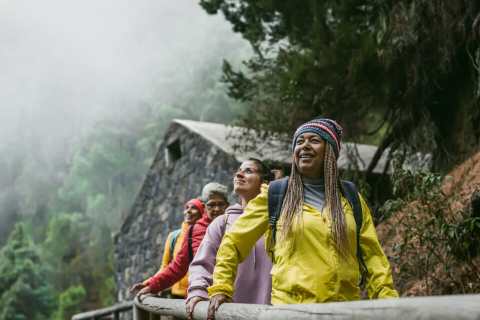 Group of women with different ages and ethnicities having fun walking in foggy forest - Adventure and travel people concept