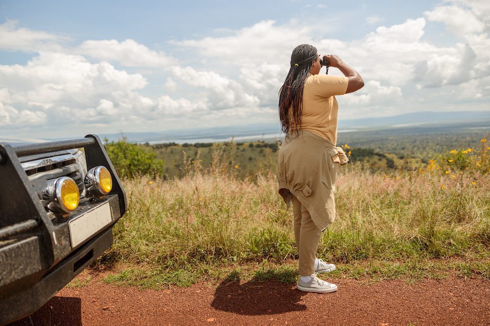 Full-length of African American female guide looking for wildlife in Africa