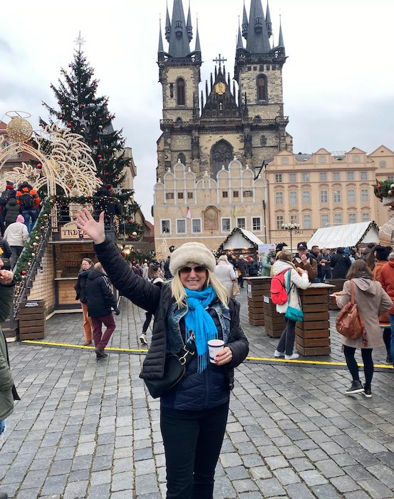 Carolyn stands with her arms up in the Prague Christmas Market