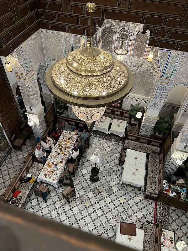 Looking down at a A group enjoys dinner at Ryad Nejjarine in Fes, Morocco