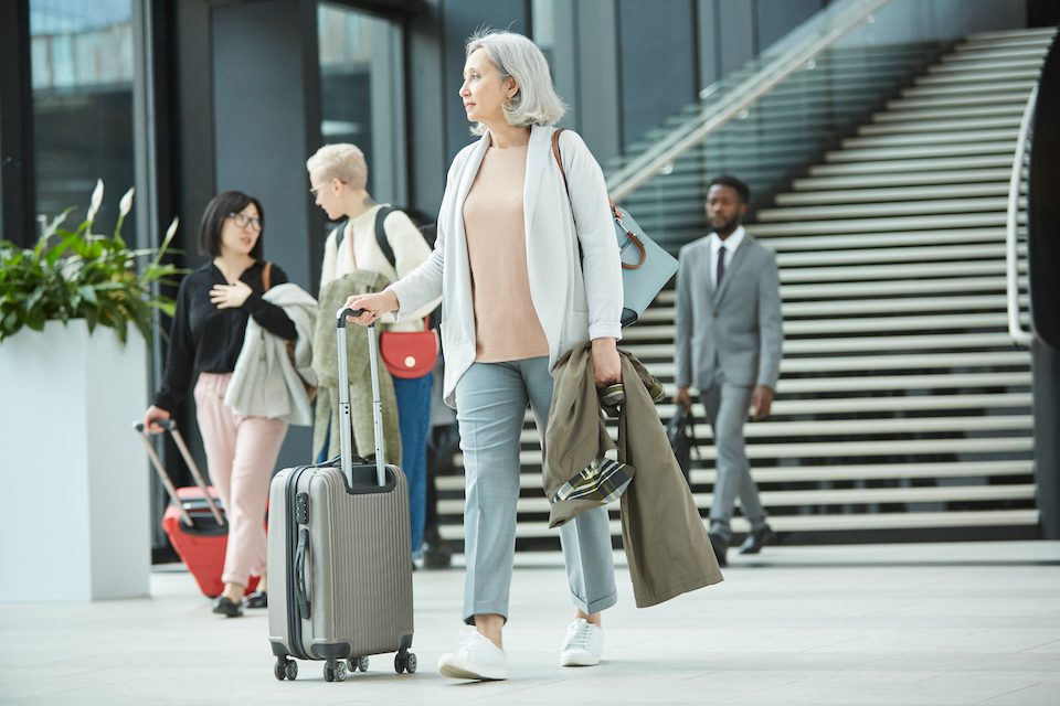 senior woman walking along airport hall with her luggage, in an age-friendly airport