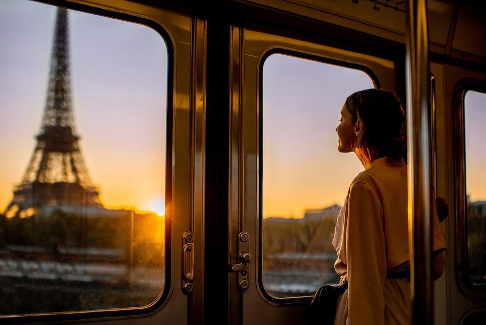 Woman enjoying view on the Eiffel tower from the subway train during the sunrise in Paris