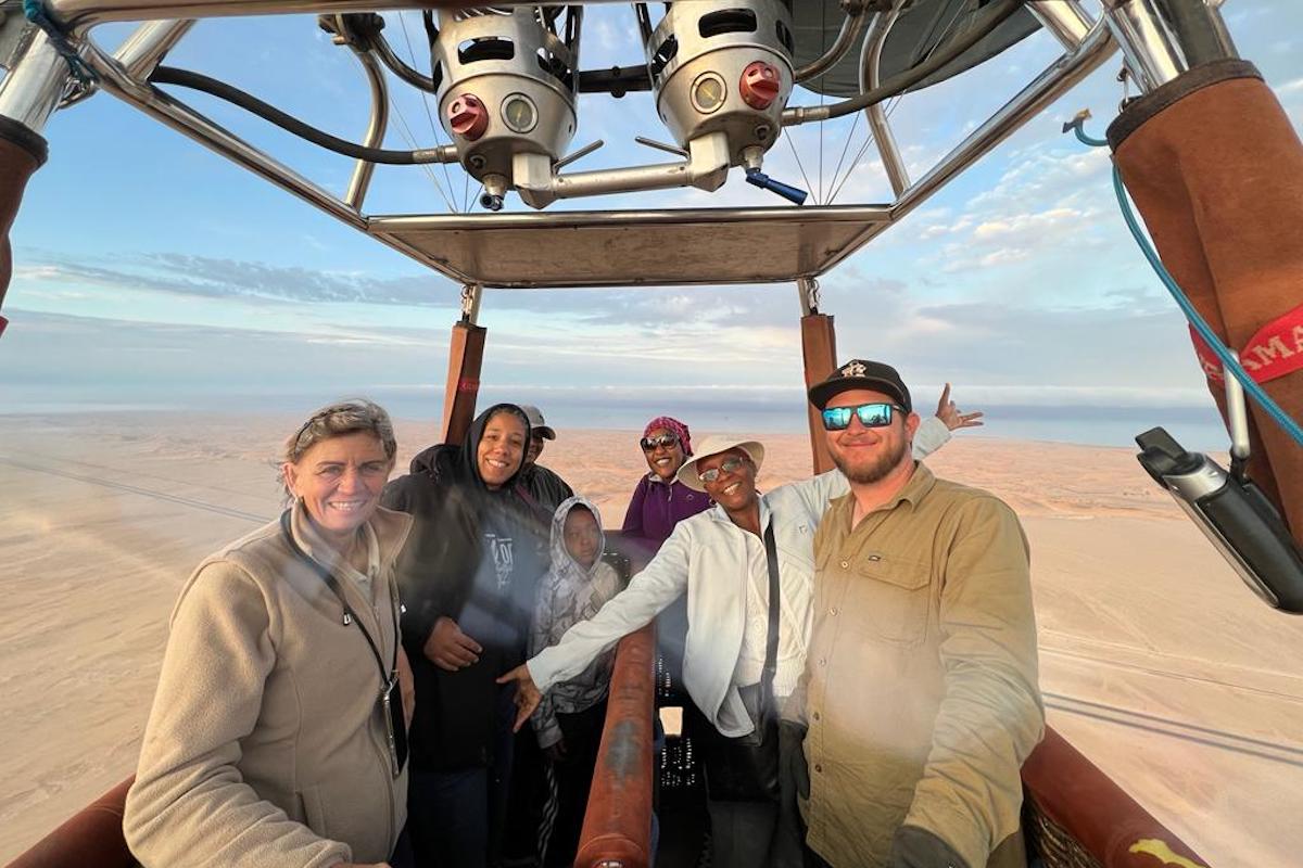 A group of passengers and crew enjoy a hot air balloon ride above the Namib desert