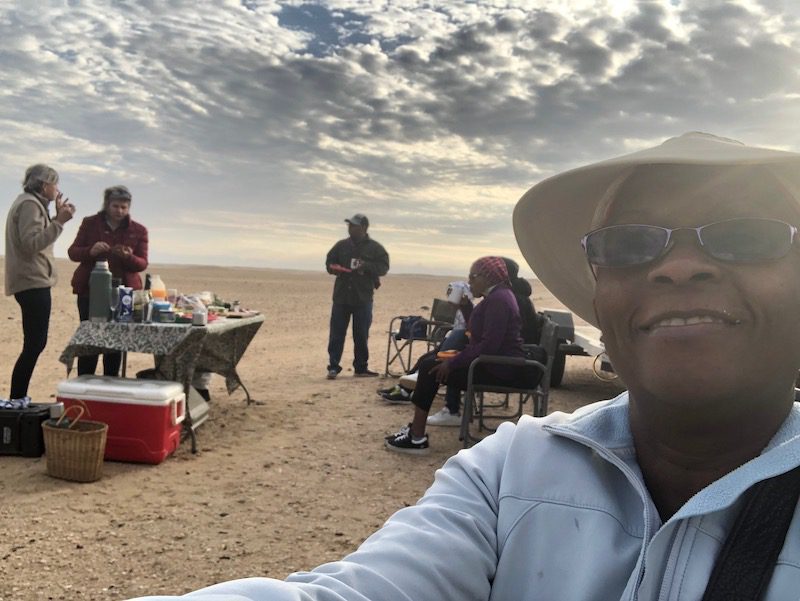 A group of people enjoy breakfast after their hot air balloon safari experience in the Namib Desert