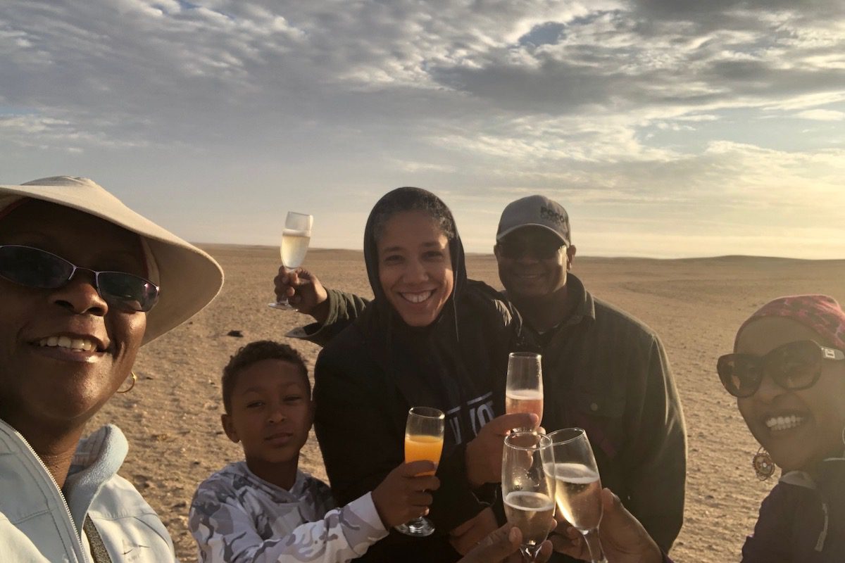 A group of people toast champagne after their hot air balloon safari experience in the Namib Desert