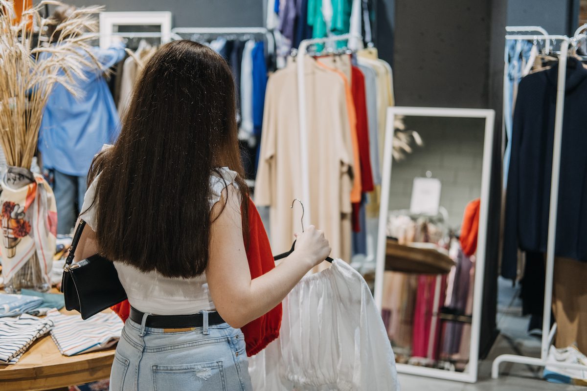 Second hand. Sustainable fashion. Young Latina woman buying used sustainable clothes from second hand shop