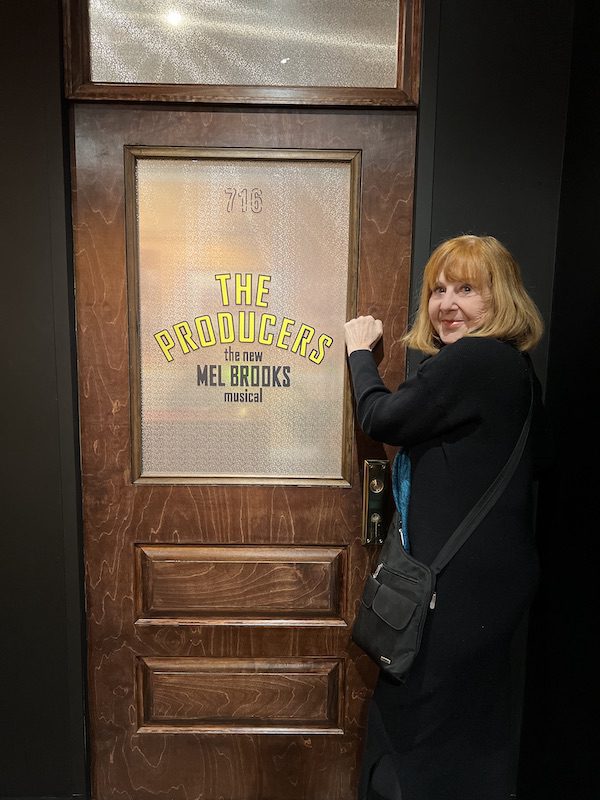 Diana Eden knocks on a door that says "The Producers" 1920s classic Hollywood costume in the Museum of Broadway NYC