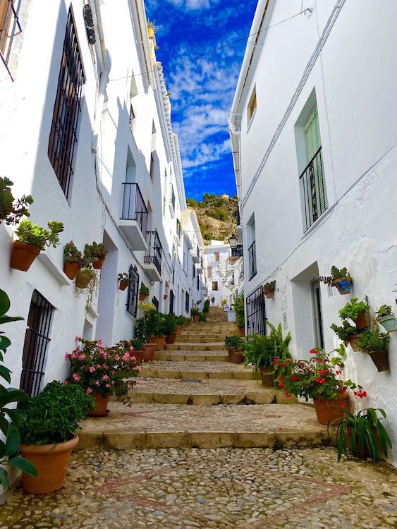 Steps leading between rows of white buildings in Frigliana, Spain