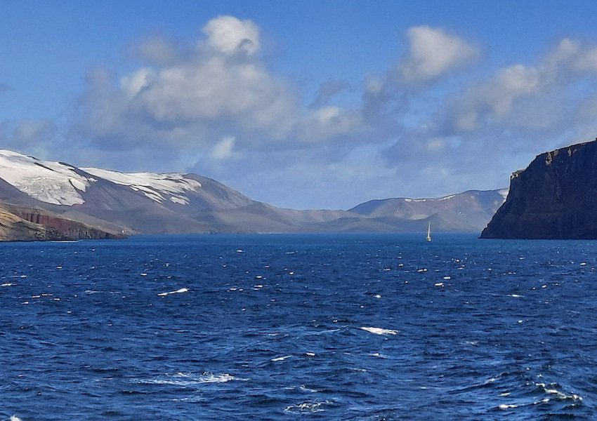A small sailboat carries researches over the Deception Island caldera in Antarctica