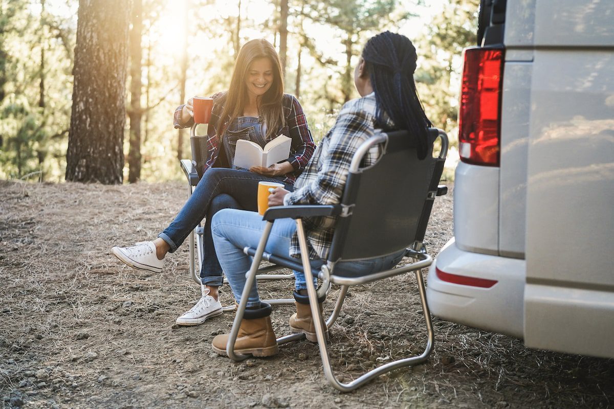 Two woman enjoy a coffee sitting on a camp site