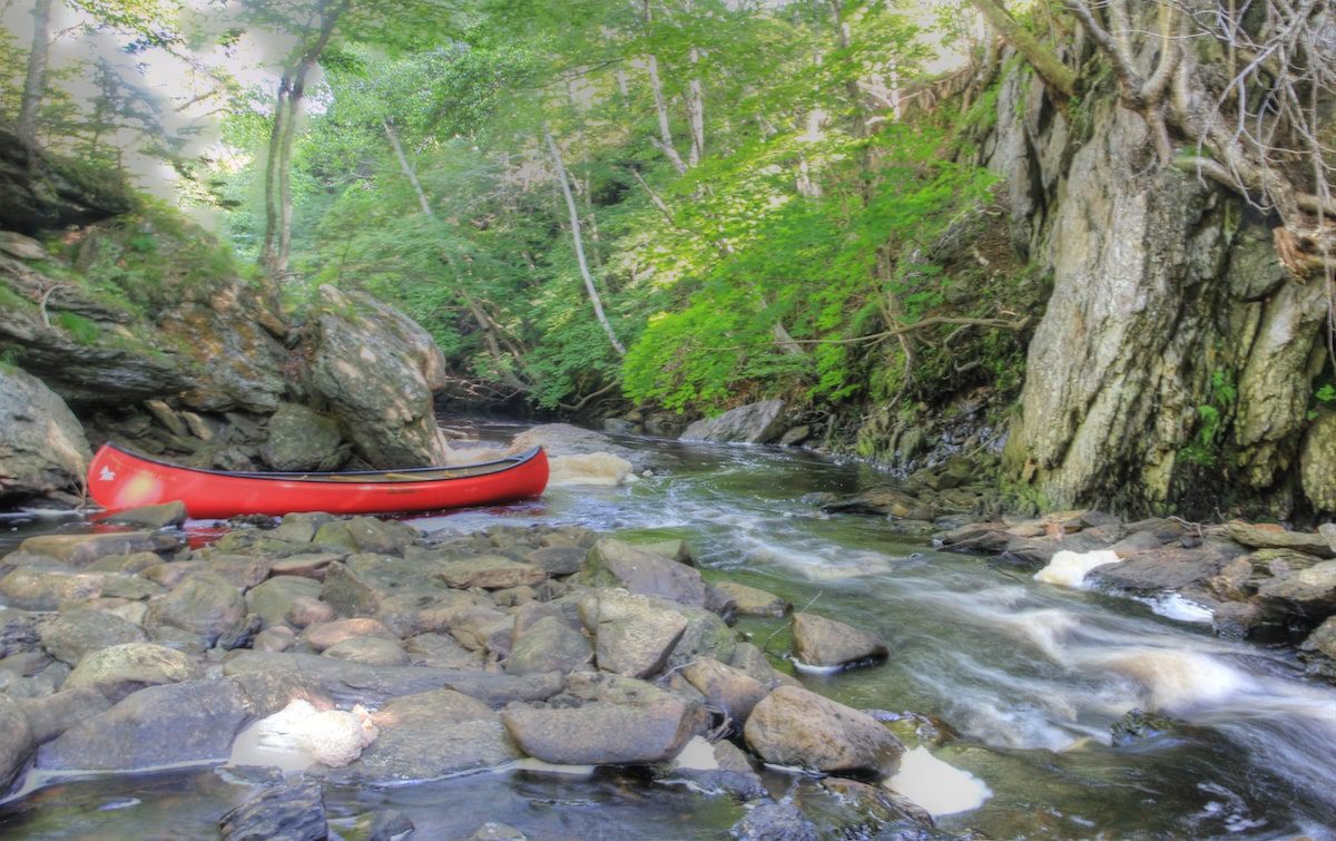 A red canoe sits on a river bed in Nova Scotia, during Sandra Phinney's project of learning to slow travel at home