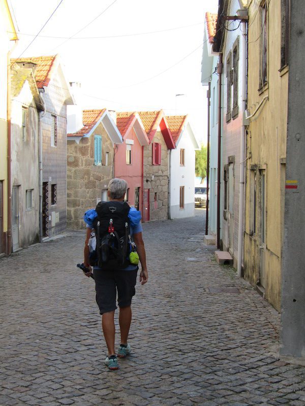 A woman walks past old houses in a village along the Camino de Santiago