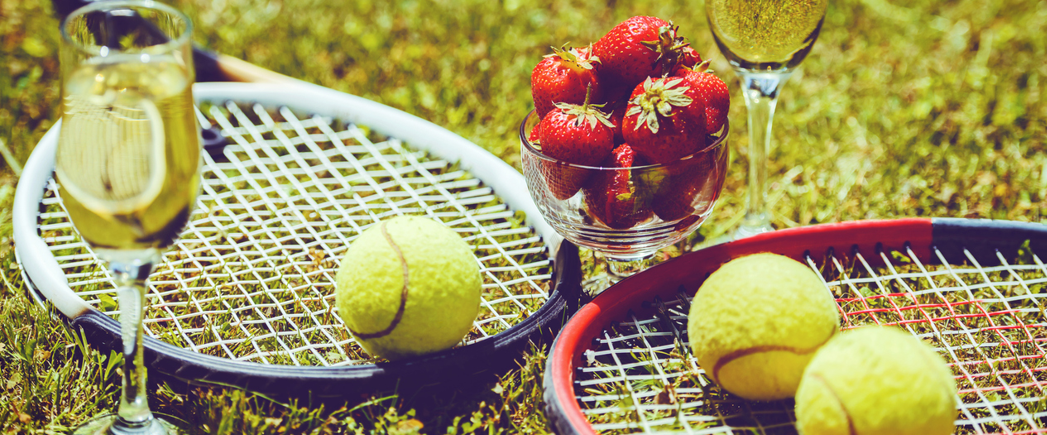 two tennis racquets with champagne and strawberries