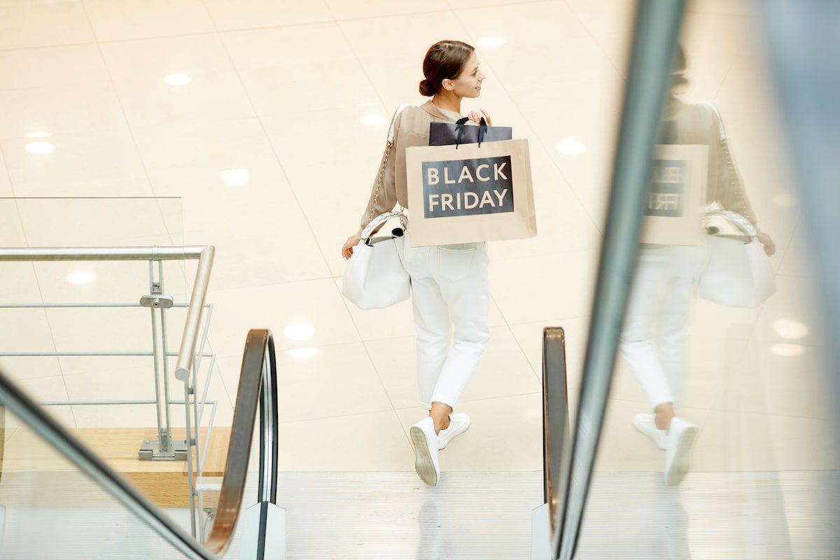 A woman walks with a shopping bag with Black Friday travel deals