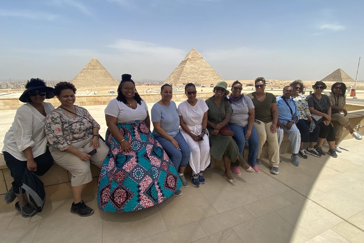 A group of women from Pack Light Global's group trip to Egypt pose in front of the Great Pyramids