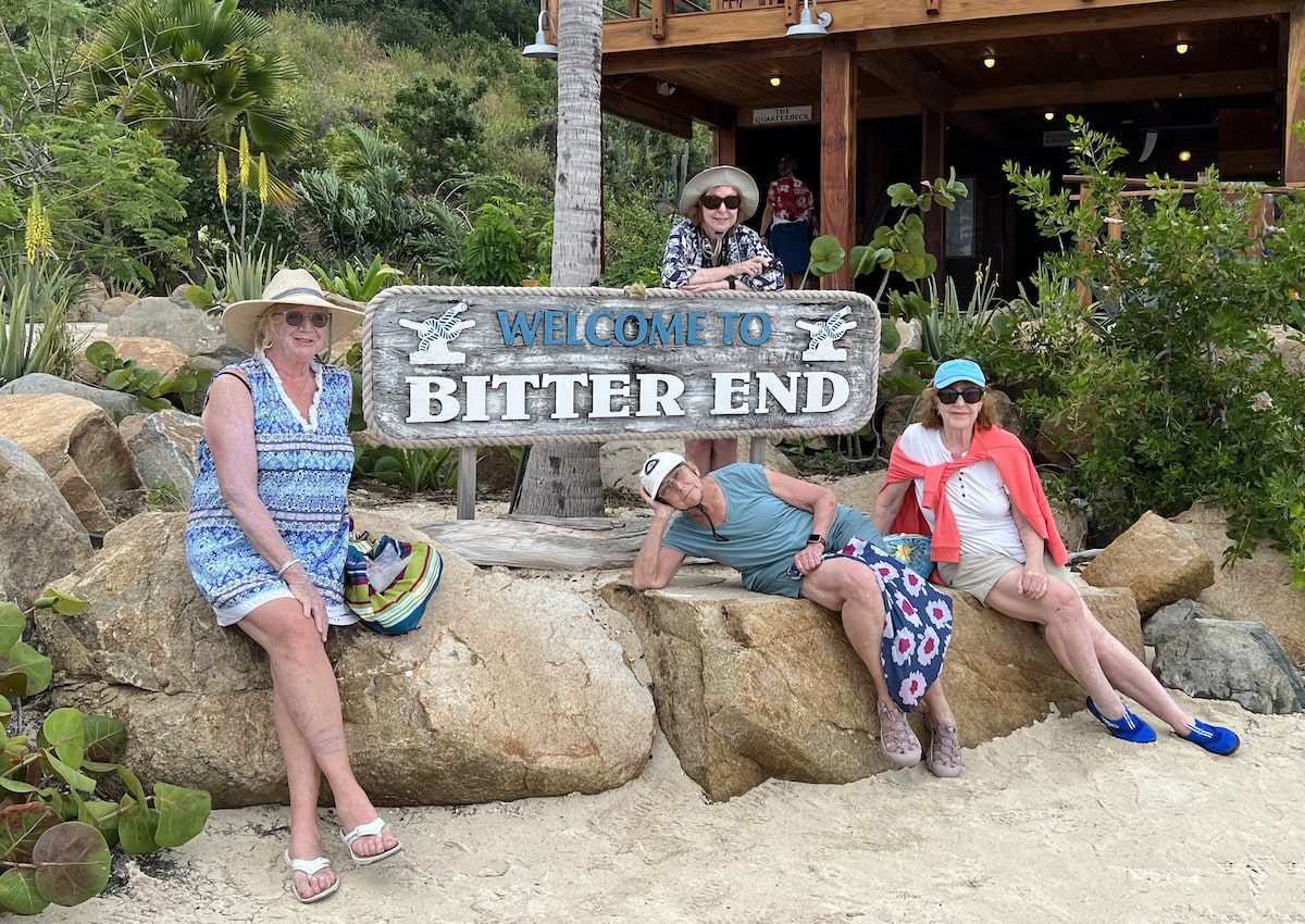 A group of friends pose in front of the Bitter End sign on a sailing for seniors trip in the British Virgin Islands