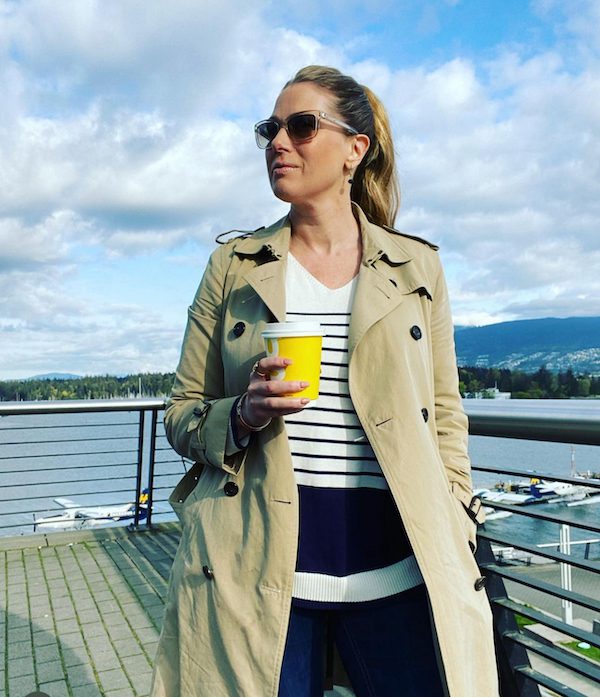 Dawn Chubai holding a cup of coffee next to the waterfront in Vancouver BC