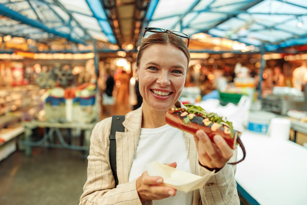 A woman enjoys a sandwich at an international food market