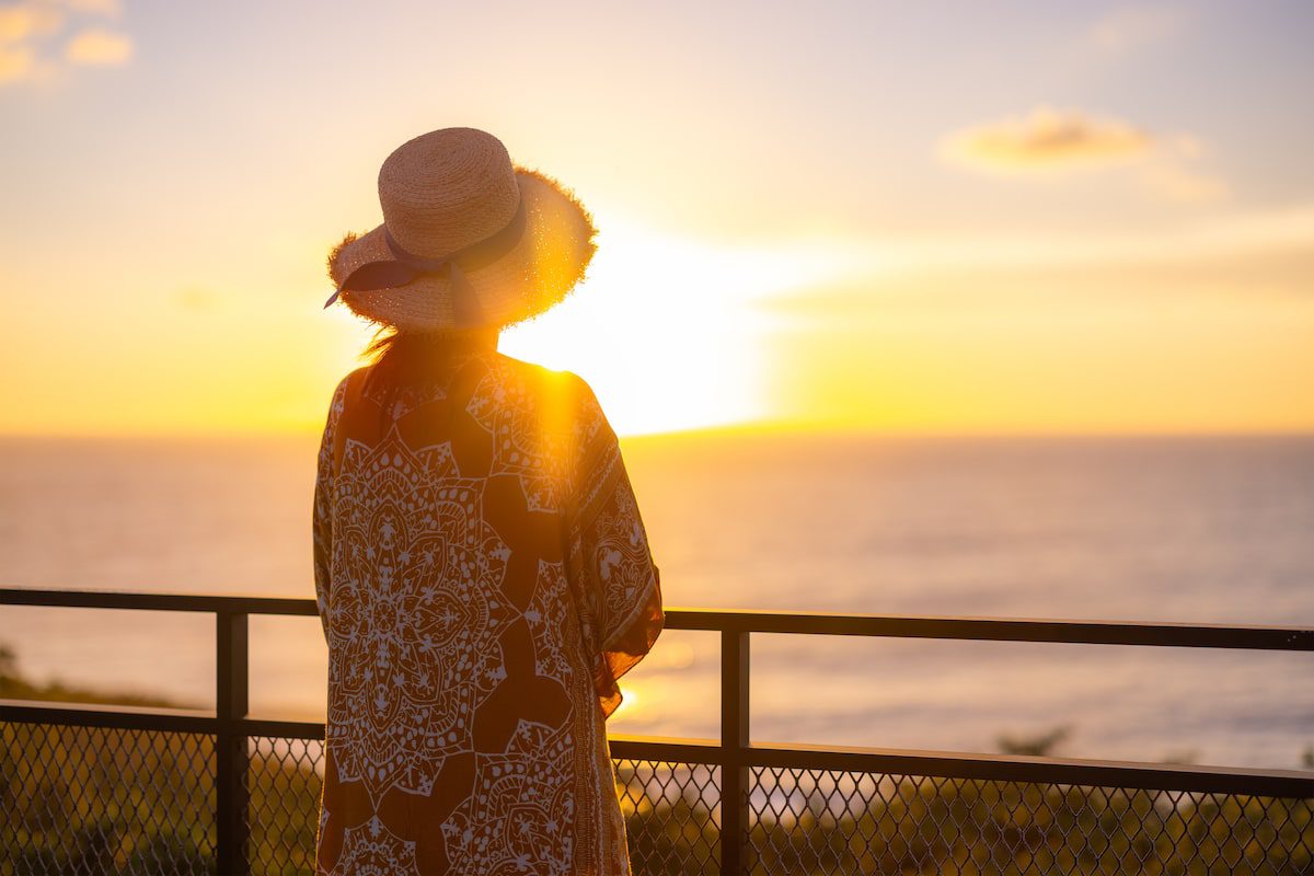 A woman looks out to the sunset, learning how to be alone during widows travel.