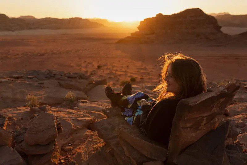 women sitting down in the jordan desert watching the sunset