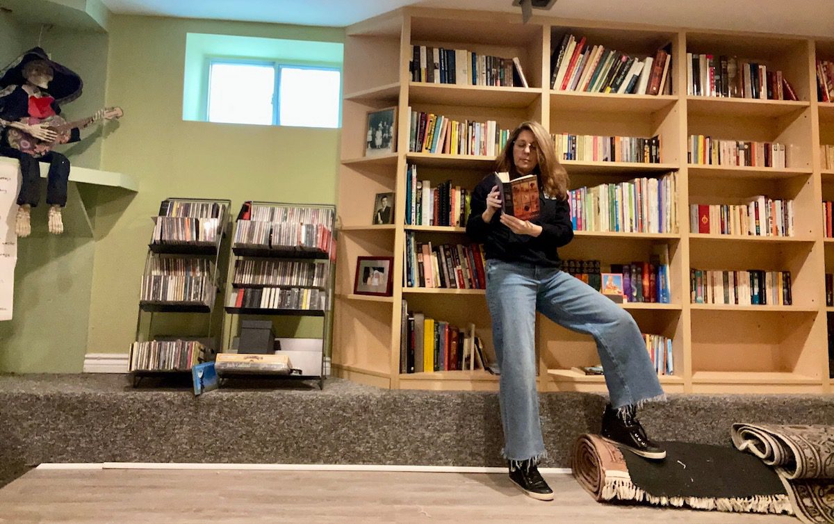Erica Ehm reads a book in front of her newly organized book shelf after decluttering her home.