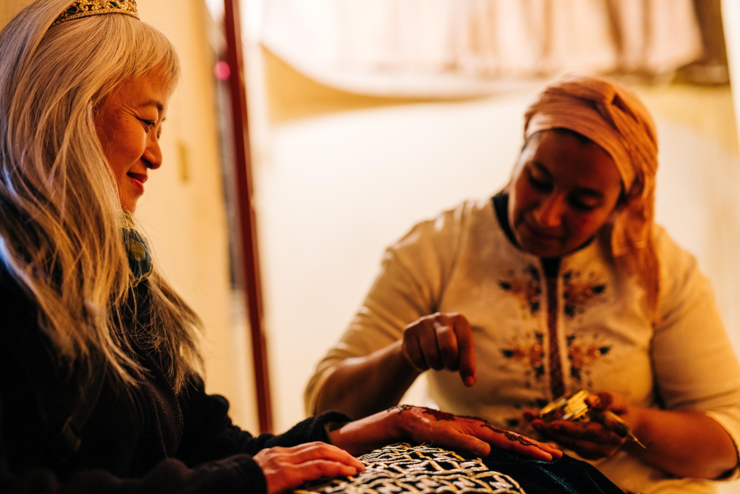 two women sitting down together. one women showing how to sew.