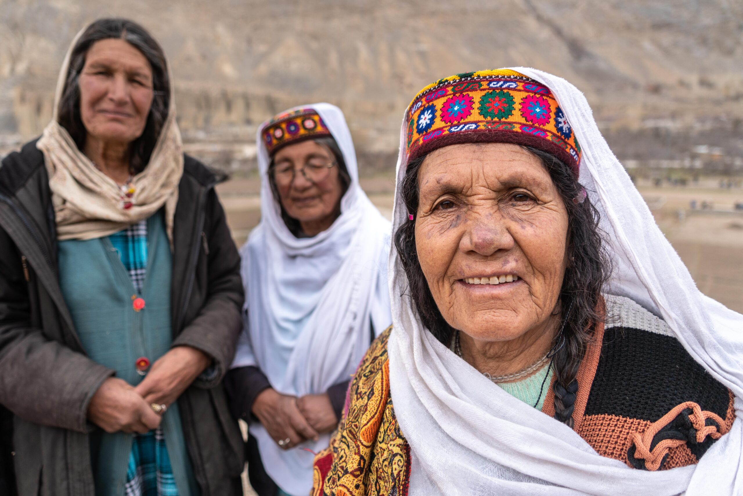 three pakistani women smiling dressed in traditional pakistani attire