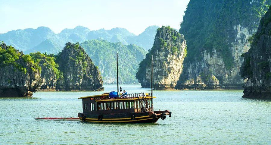 a small sailing boat anchored in the water in between halong bay in vietnam