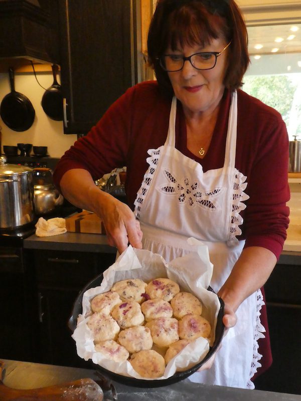 A woman holding a tray of homemade biscuits
