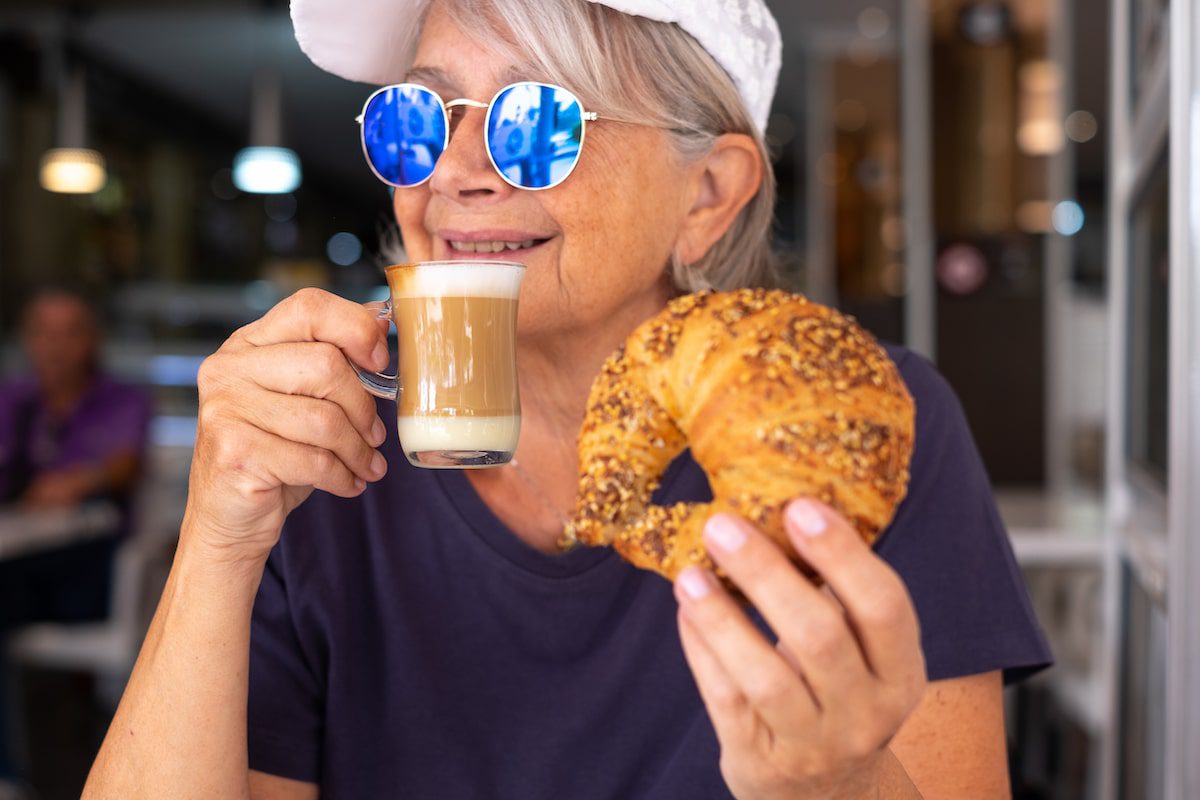 A woman enjoys a croissant and coffee on a food tour in Paris