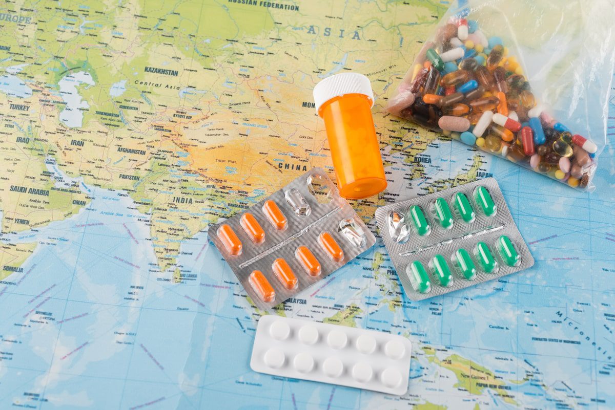 A map with different medications laid on top. Learn how to travel with medications with these tips.