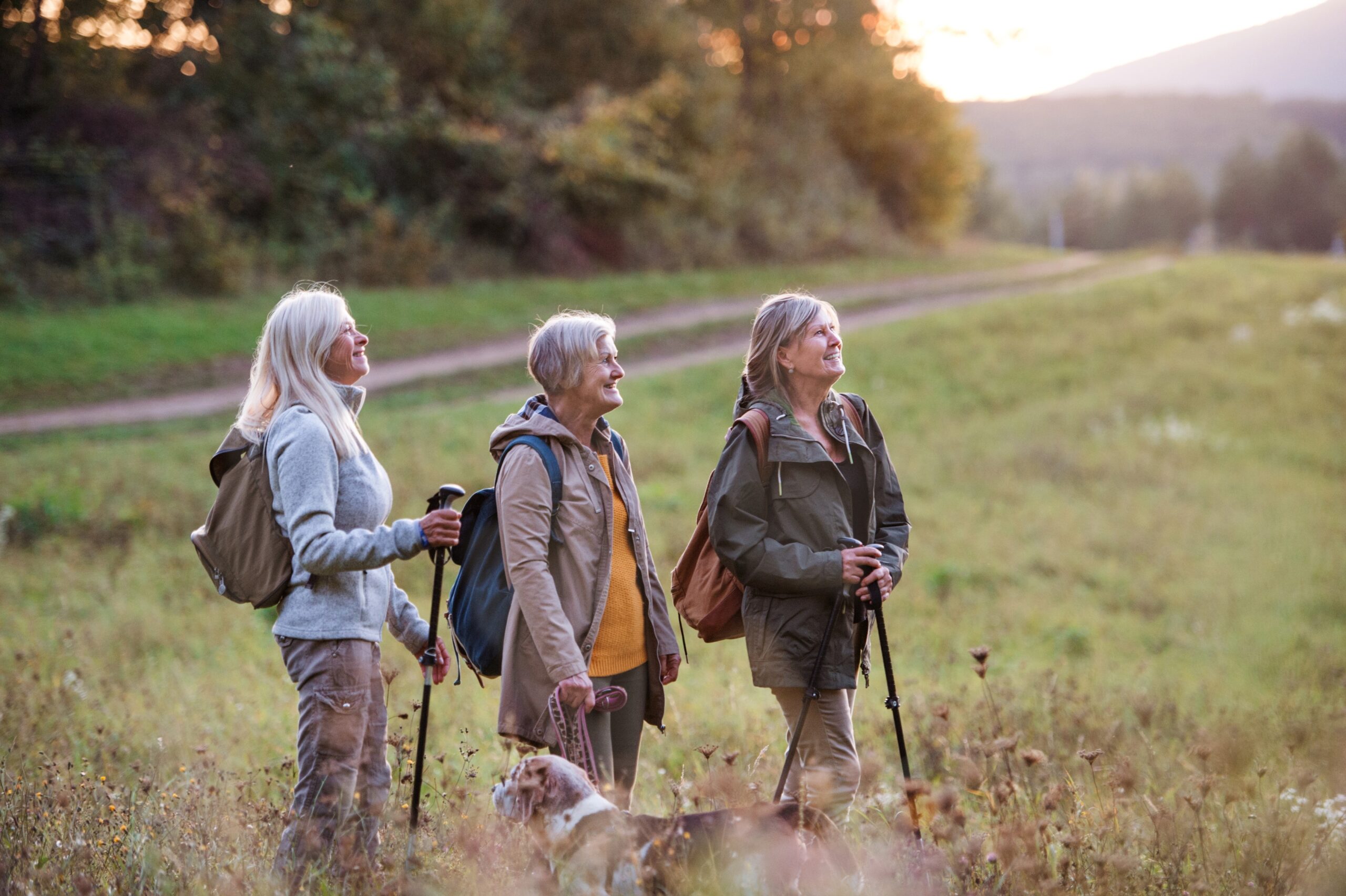 three senior women hiking in a field